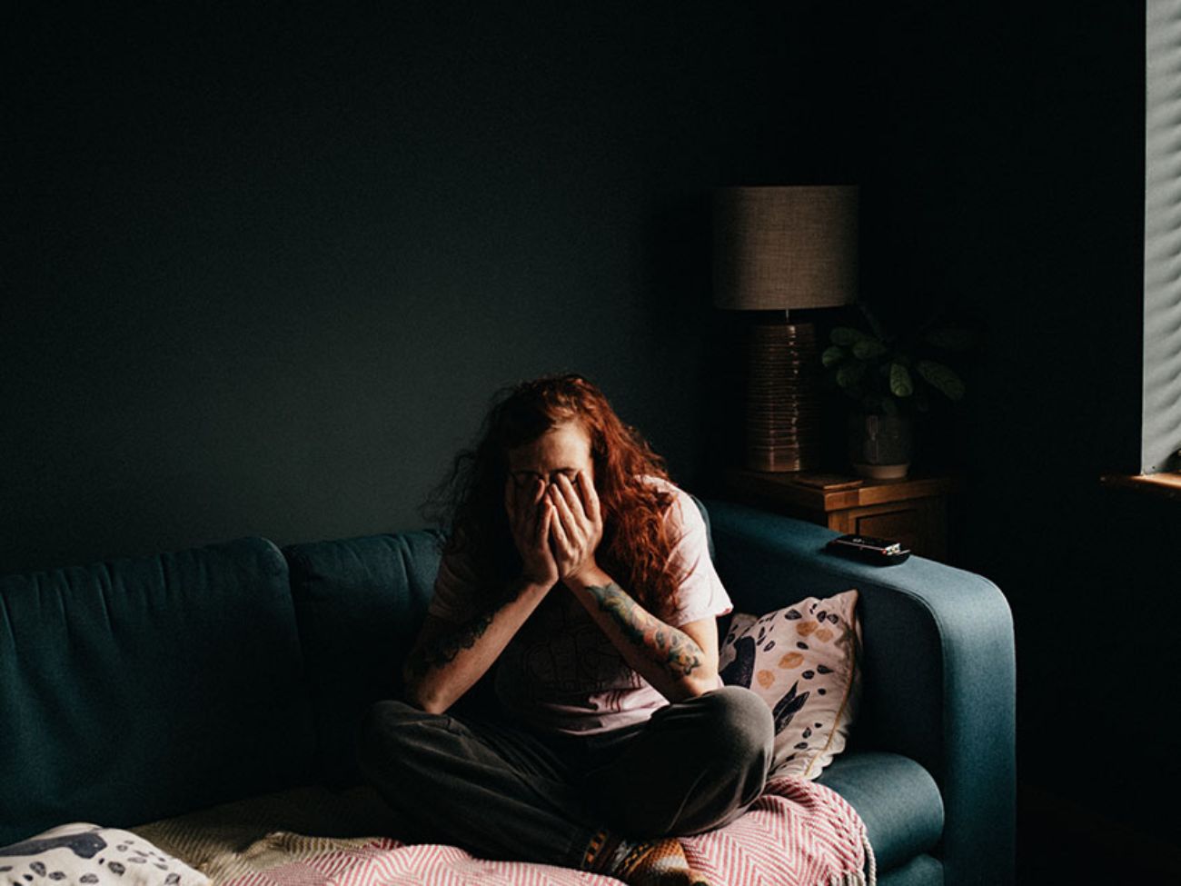 vrouw op bank met handen voor gezicht