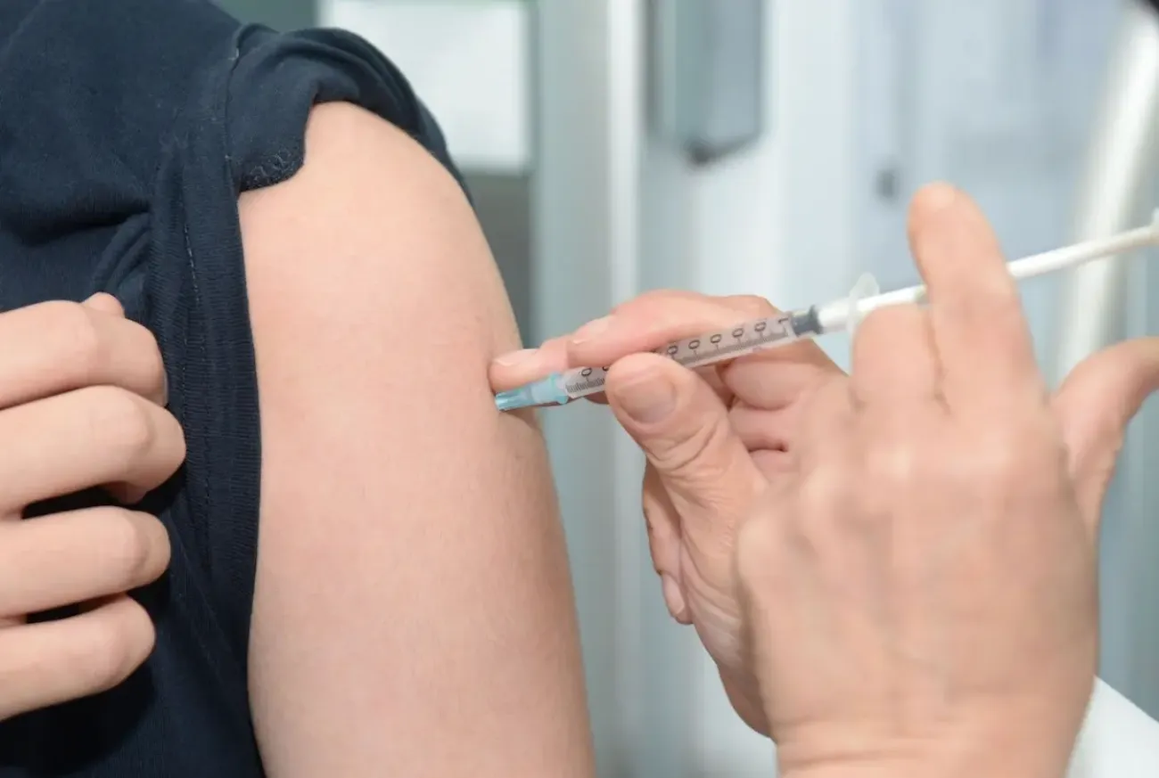 Arts zet griepprik in iemands arm