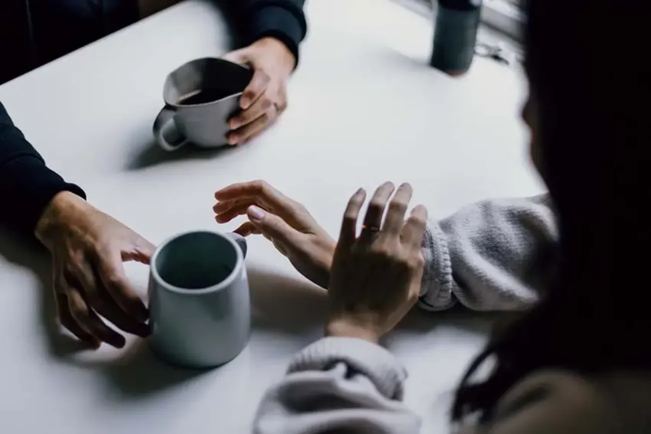 Twee mensen aan tafel met een kop koffie