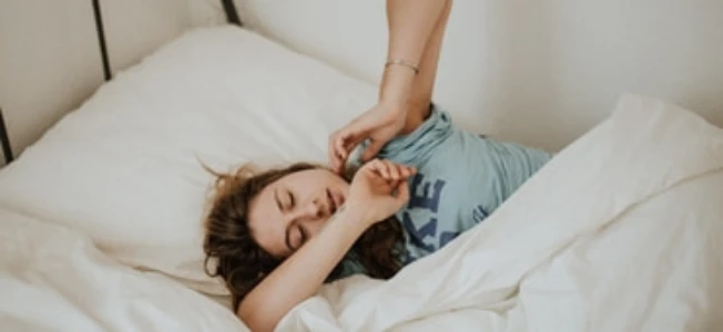 vrouw in bed rekt zich uit